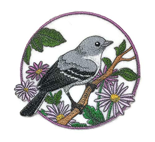 Embroidered patch of a bird on a branch with flowers and leaves in a circular design.