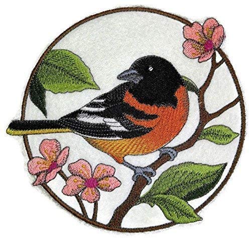 Embroidered patch of a bird on a branch with flowers and leaves.