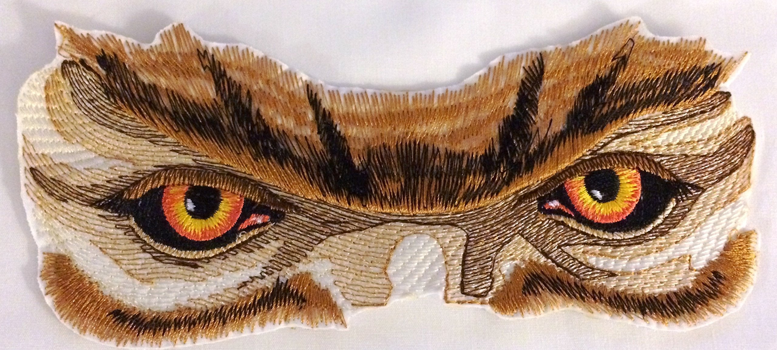 Embroidered patch of an owl's face with detailed feathers and vibrant eyes on a white background.