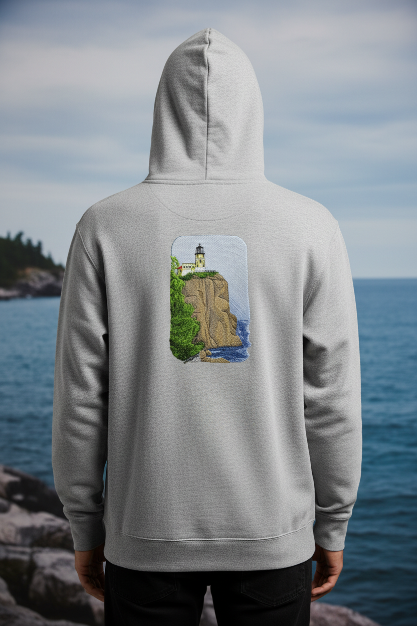 Model wearing hoodie with Split Rock Lighthouse patch on back with coastal view